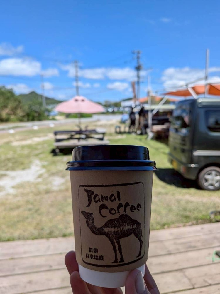 Jamal Coffeeのロゴが入ったコーヒーカップと、あざま共同売店の庭